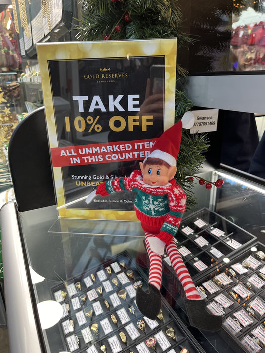 Christmas elf sat in front of the Gold Reserves Black Friday poster so you can get 10% off jewellery