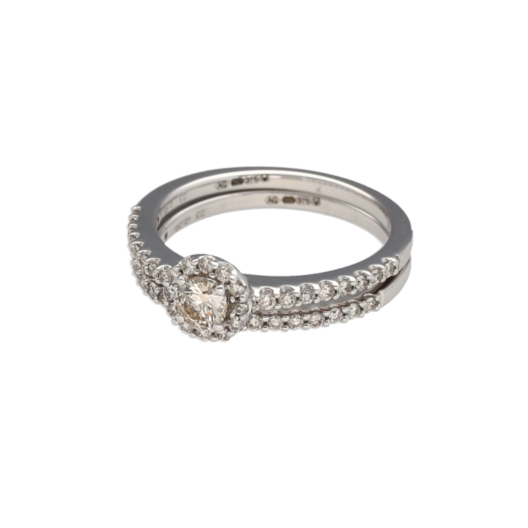 Bring coordinated brilliance and timeless romance to your collection with this pre-owned 9ct white gold diamond halo set wedding band set—perfect for lasting elegance and symbolic style.
Design: The engagement-style ring features a central brilliant cut diamond surrounded by a diamond halo and diamond-set shoulders. The matching wedding band, approximately 1.5mm wide, is set with a fine row of small brilliant cut diamonds for a seamless pairing.