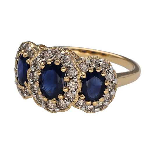 New 9ct Yellow Gold 0.85ct Diamond & Sapphire Set Cluster Trilogy Ring in size N with the weight 4.80 grams. The front of the ring is 12mm high and the center sapphire stone is 7mm by 5mm. There is approximately 0.85ct of diamond content in total