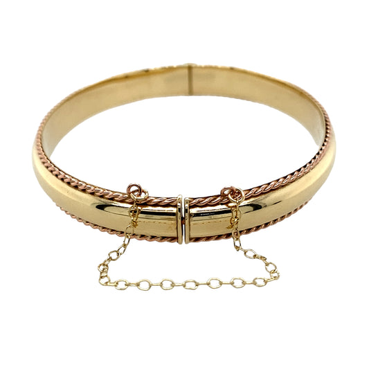 Preowned 9ct Yellow and Rose Gold Clogau Rope Trim Hinged Bangle with the weight 12.90 grams and has a safety chain attached. The bangle width is 9mm and bangle diameter 6.5cm