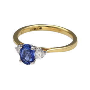 New 18ct Yellow and White Gold Diamond & Sapphire Trilogy Ring in size N with the weight 2.90 grams. The sapphire stone is 7mm by 5mm and there is approximately 25pt of diamond content in total