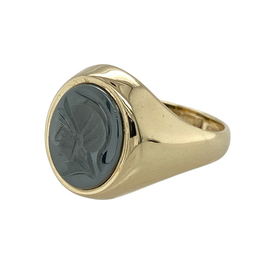 Bring bold character and vintage appeal to your collection with this pre-owned 9ct yellow gold hematite centurion signet ring, combining strong design with timeless style—ideal for both statement wear and everyday distinction.
Design: Featuring a 12mm by 10mm oval hematite stone engraved with a classic centurion motif, the ring offers a striking and masculine aesthetic with a touch of historical charm.