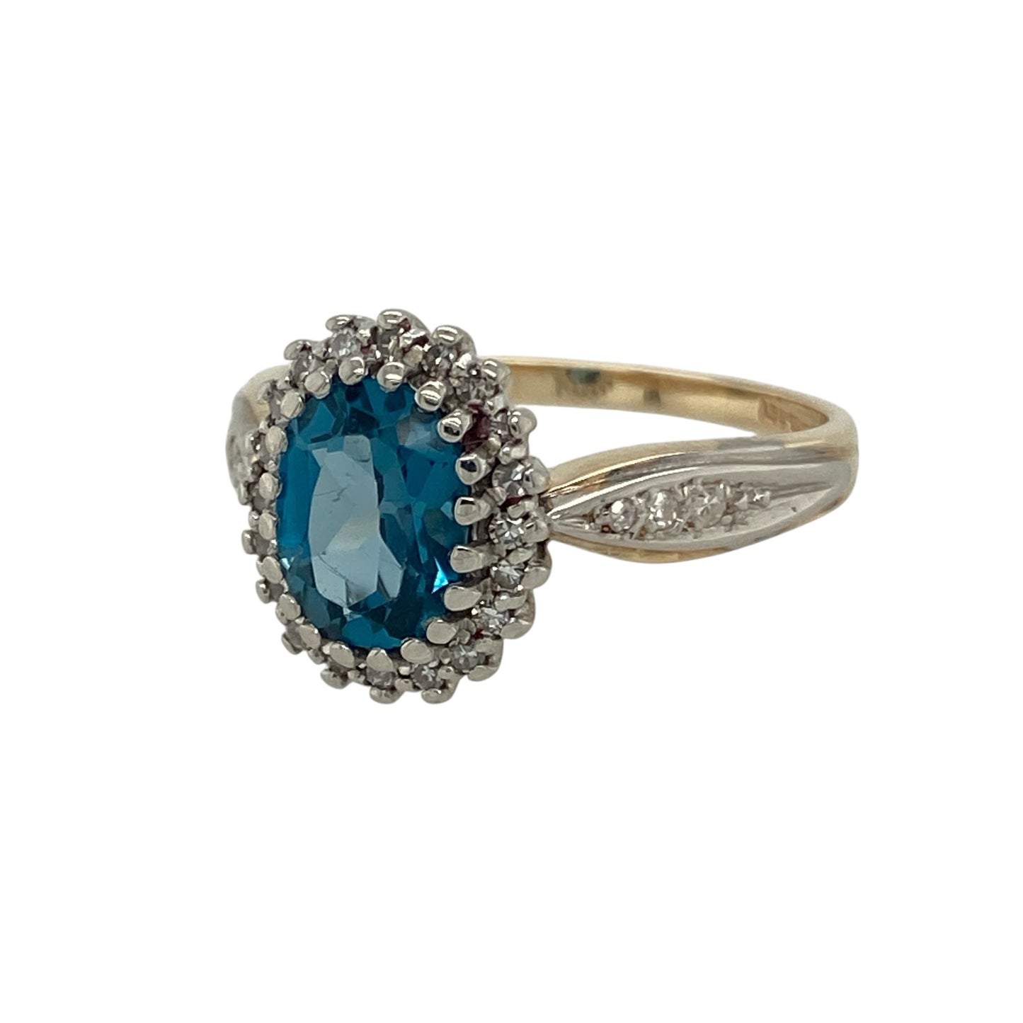 Bring vibrant colour and elegant sparkle to your collection with this pre-owned 9ct yellow gold diamond and blue topaz cluster ring, combining timeless sophistication with eye-catching brilliance—perfect for special occasions or refined everyday wear.
Design: The ring features an oval blue topaz centre stone measuring 8mm by 6mm, surrounded by a halo of glittering diamonds that continue along the shoulders, creating a luxurious and balanced cluster design.