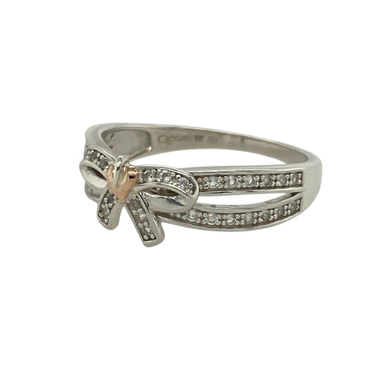 Bring feminine elegance and subtle sparkle to your collection with this pre-owned 925 silver and 9ct rose gold white topaz set Clogau bow ringβperfect for adding a touch of charm and sophistication to any look.
Design: The ring features a beautifully sculpted bow design at the front, measuring 7mm high, adorned with shimmering white topaz stones for a delicate sparkle. The graceful shape symbolises love, unity, and timeless elegance.