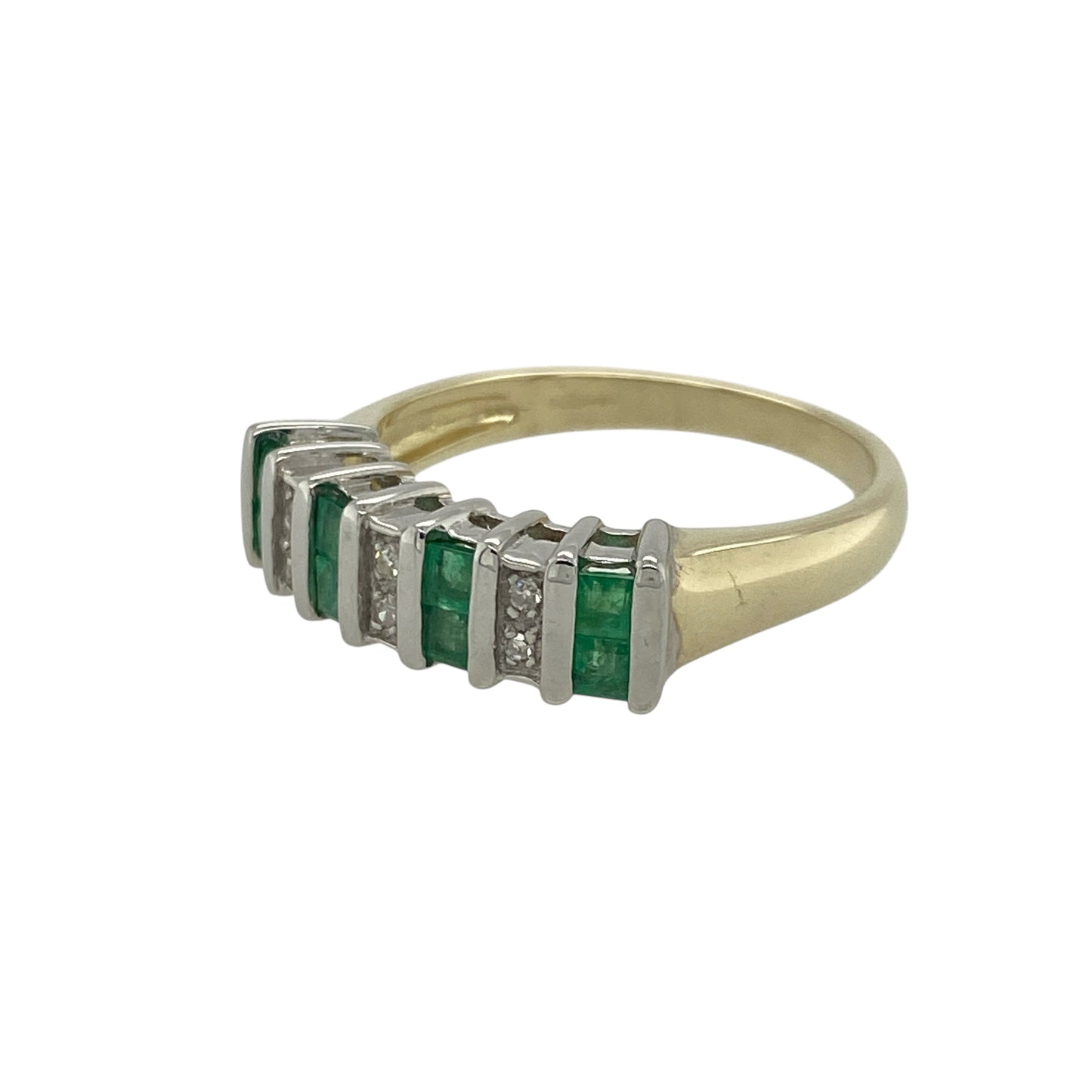 Add rich colour and classic elegance to your collection with this pre-owned 9ct yellow gold diamond and emerald set band ring — a timeless piece that beautifully combines vibrant gemstones with refined sparkle.
Design: The front of the 5mm wide band features a striking row of princess-cut emeralds, each separated by small sparkling diamonds, creating a seamless flow of colour and light across the design.