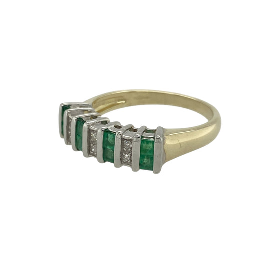 Add rich colour and classic elegance to your collection with this pre-owned 9ct yellow gold diamond and emerald set band ring — a timeless piece that beautifully combines vibrant gemstones with refined sparkle.
Design: The front of the 5mm wide band features a striking row of princess-cut emeralds, each separated by small sparkling diamonds, creating a seamless flow of colour and light across the design.