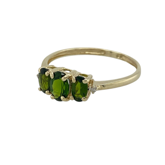 Pre-owned 9ct Yellow Gold Diamond & Chrome Diopside Set Trilogy Ring in size P with the weight 1.20 grams. The center oval stone is 6mm by 4mm and there is a small diamond on either side of the three chrome diopside stones
