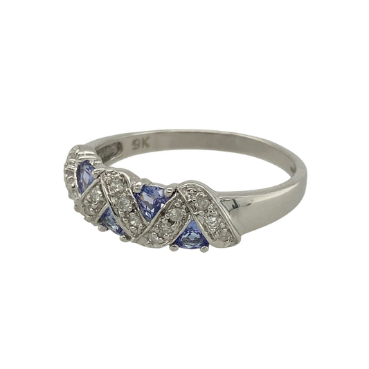 Bring soft colour and refined sparkle to your collection with this pre-owned 9ct white gold diamond and tanzanite set band ring—a stylish blend of elegance and contemporary design.
Design: The ring features alternating 3mm round tanzanite stones framed by a criss-cross diamond set pattern across the front of the 7mm wide band, adding texture and brilliance to the look.