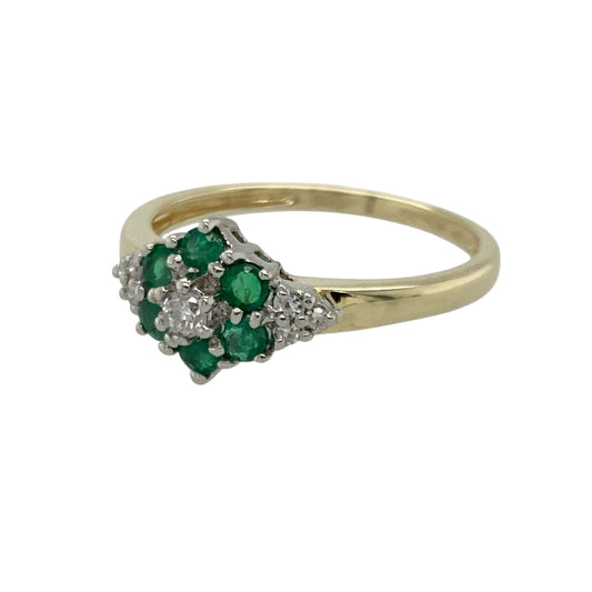 Bring vibrant colour and delicate sparkle to your collection with this pre-owned 9ct yellow gold diamond and emerald flower cluster ring—an elegant piece offering timeless charm and refined beauty.
Design: This size R ring features a floral cluster formed from 2mm round emeralds surrounding a central diamond, with three additional small diamonds set on either side to enhance the brilliance and balance of the design.