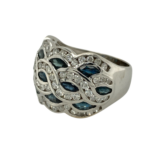 Bring bold elegance and luxurious presence to your jewellery collection with this pre-owned 18ct white gold diamond and sapphire set wide band ring, a striking design that combines rich colour with refined sparkle.
Design: The ring features a wide band front set with deep blue sapphires and sparkling diamonds arranged across the top, creating a balanced and eye-catching display. The front of the ring measures approximately 14mm in width, giving it a strong and statement-making profile.