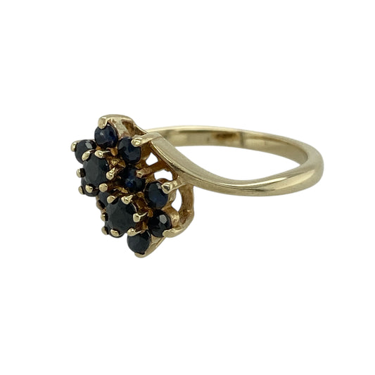 Bring classic colour and elegant sparkle to your jewellery collection with this pre-owned 9ct yellow gold sapphire set double cluster ring, a beautifully balanced design with timeless appeal.
Design: The ring features a double cluster arrangement of sapphires, creating a striking and symmetrical focal point. The decorative front measures 10mm high, offering a noticeable yet refined presence on the hand.