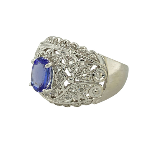 Bring bold elegance and refined colour to your jewellery collection with this pre-owned 14ct white gold diamond & tanzanite set ornate dress ring, a striking piece with impressive presence and intricate detail.
Design: The ring features an oval tanzanite stone measuring 8mm by 6mm, forming a rich violet-blue focal point. The ornate front measures 17mm high, creating a dramatic and eye-catching dress-ring silhouette accented with diamonds for added sparkle.