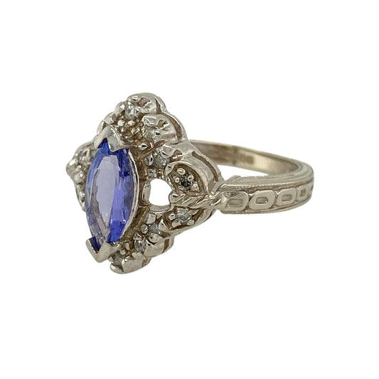 Bring elegant colour and intricate detail to your jewellery collection with this pre-owned 14ct white gold diamond and tanzanite set ornate ring, a striking piece with refined character.
Design: The ring showcases a marquise-cut tanzanite at the centre, framed by decorative detailing and diamond accents that enhance its graceful, elongated shape and add refined sparkle.