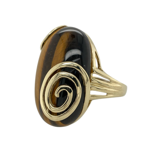Bring bold character and natural beauty to your jewellery collection with this pre-owned 9ct yellow gold tiger’s eye set swirl edge ring, offering a striking statement design with impressive presence—perfect for those who love standout jewellery.
Design: The ring features a large oval tiger’s eye stone measuring approximately 29mm by 19mm, framed by a decorative swirl-edge setting that enhances the stone’s rich, chatoyant tones and flowing natural pattern.