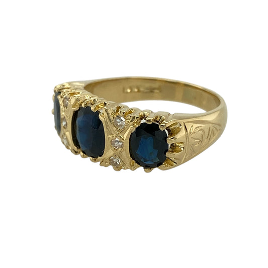 Bring rich colour and timeless vintage elegance to your jewellery collection with this pre-owned 18ct yellow gold diamond and sapphire set vintage style ring, offering a bold design with refined detail—perfect for special occasions or collectors of classic jewellery.
Design: The ring features a central oval sapphire measuring approximately 7mm by 6mm, flanked by two oval sapphires measuring approximately 6mm by 5mm, with three diamonds set between the sapphires to add balance and sparkle.
