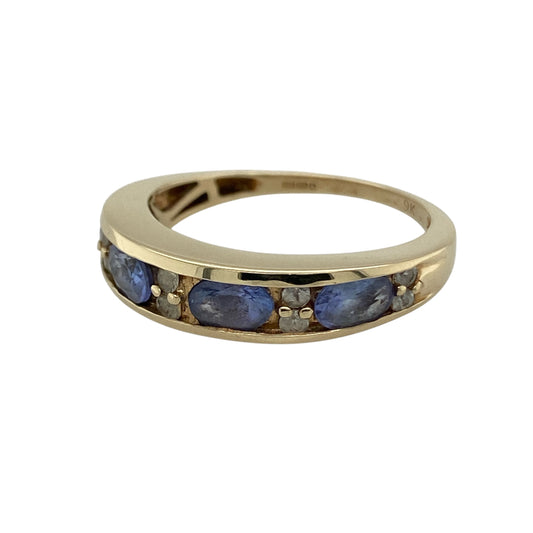 Add vibrant colour and sparkle to your jewellery collection with this pre-owned 9ct yellow gold tanzanite and cubic zirconia set band ring—an elegant statement piece perfect for both everyday wear and special occasions.
Design: The front of the band measures approximately 6mm wide and is composed of four oval-cut tanzanite stones, displaying beautiful violet-blue tones.