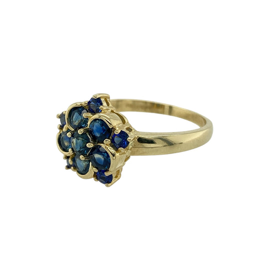 Add timeless colour and delicate elegance to your jewellery collection with this pre-owned 9ct yellow gold sapphire flower cluster ring, featuring a classic floral-inspired design—perfect for everyday wear or as a meaningful gift.
Design: The ring showcases a pretty flower cluster arrangement with a sapphire at the centre measuring approximately 3mm, surrounded by additional sapphires that form petal-like accents. The floral layout creates a balanced and eye-catching display of deep blue colour.