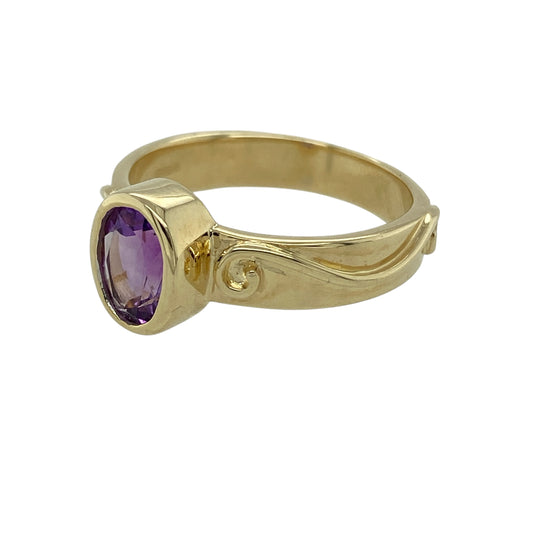 Add elegant colour and distinctive Welsh design to your jewellery collection with this pre-owned 9ct Clogau amethyst swirl band ring, featuring a graceful flowing style—perfect for everyday wear or a meaningful gift.
Design: The ring showcases a beautiful oval amethyst measuring approximately 7mm by 5mm, highlighted by a graceful swirl design that draws the eye toward the centre stone. The flowing lines create a soft and elegant silhouette.