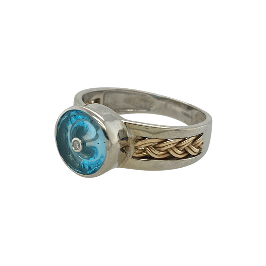 Add bold colour and distinctive detail to your jewellery collection with this pre-owned 9ct white and yellow gold diamond blue stone ring, featuring an eye-catching two-tone design—perfect as a statement dress ring or standout everyday piece.
Design: The ring showcases a striking round blue centre stone measuring approximately 9mm, creating a bold focal point. Diamond accents and plaited detailing across the shoulders add texture and sparkle, enhancing the overall design.