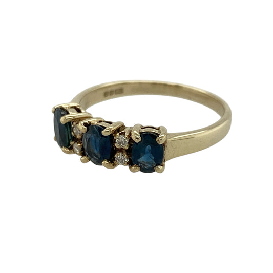 Add timeless elegance and rich colour to your jewellery collection with this pre-owned 9ct yellow gold diamond and sapphire set trilogy ring—an eye-catching and meaningful piece perfect for everyday wear or special occasions.
Design: This ring features three oval sapphire gemstones, each measuring approximately 5mm by 3mm, arranged in a classic trilogy formation. Two sparkling diamonds are set between each sapphire, adding extra brilliance and enhancing the overall design.