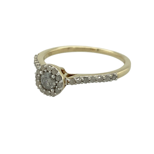 Add elegant sparkle and timeless style to your jewellery collection with this pre-owned 9ct yellow gold diamond set halo ring—an eye-catching piece perfect for special occasions or everyday wear.
Design: This ring features a central brilliant-cut diamond of approximately 0.25ct, surrounded by a halo of smaller diamonds that enhance its size and brilliance. Additional diamonds are set along the shoulders for extra sparkle.