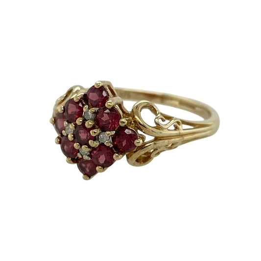 Add rich colour and classic elegance to your jewellery collection with this pre-owned 9ct yellow gold diamond and ruby cluster ring, featuring a bold floral-inspired design—perfect for special occasions or standout everyday wear.
Design: The ring features a cluster of nine round rubies, each approximately 3mm, arranged to create a striking and vibrant focal point, with small diamonds set in between adding extra sparkle and contrast.