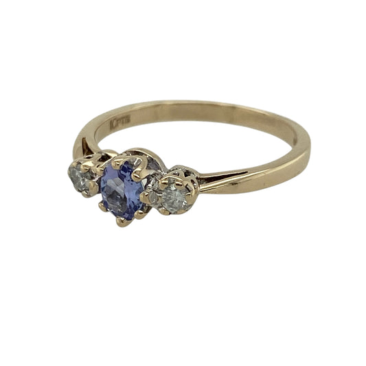 Add vibrant colour and elegant sparkle to your jewellery collection with this pre-owned 9ct yellow gold diamond and tanzanite trilogy ring, featuring a classic three-stone design—perfect for special occasions or everyday wear.
Design: The ring showcases an oval tanzanite measuring approximately 5mm by 3mm at its centre, flanked by a diamond on either side for a balanced and refined look.