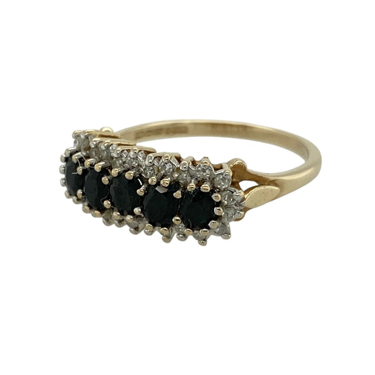 Add vibrant colour and elegant sparkle to your jewellery collection with this pre-owned 9ct yellow gold diamond and sapphire cluster band ring, featuring a bold and eye-catching design—perfect for special occasions or everyday wear.
Design: The ring showcases five oval sapphires across the front, each surrounded by sparkling diamonds, creating a beautiful multi-cluster effect with rich blue tones and brilliant contrast.