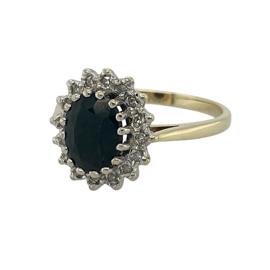Add timeless elegance and rich colour to your collection with this pre-owned 9ct yellow gold diamond and sapphire set cluster ring—an eye-catching piece with classic appeal.
Design: The ring features an 8mm by 6mm oval sapphire at the centre, surrounded by a cluster of sparkling diamonds that enhance its deep blue tone and create a bright, elegant focal point.