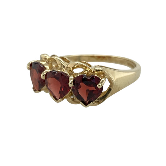Add romantic colour and timeless elegance to your jewellery collection with this pre-owned 9ct yellow gold diamond and garnet heart band ring, featuring striking heart-cut gemstones with delicate diamond detail—perfect for special occasions, meaningful gifting, or standout everyday wear.
Design: The ring showcases three heart-cut garnet stones, each measuring approximately 6mm, creating a bold and feminine band design enhanced by delicate diamond accents for added sparkle.