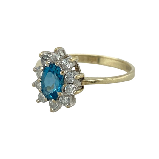 Add elegant colour and timeless sparkle to your jewellery collection with this pre-owned 9ct yellow gold blue stone and cubic zirconia cluster ring, featuring a classic gemstone design with refined brilliance—perfect for special occasions, gifting, or sophisticated everyday wear.
Design: The ring showcases a beautiful oval blue stone measuring approximately 6mm by 4mm, surrounded by sparkling cubic zirconia stones in an elegant cluster setting that enhances its colour and creates an eye-catching finish.