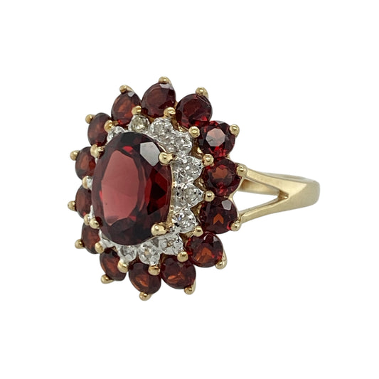 Add rich colour and timeless elegance to your jewellery collection with this pre-owned 9ct yellow gold diamond and garnet cluster ring, featuring a striking multi-gemstone design with luxurious vintage-inspired appeal—perfect for special occasions, gifting, or statement everyday wear.
Design: The ring showcases a beautiful oval garnet centre stone measuring approximately 9mm by 7mm