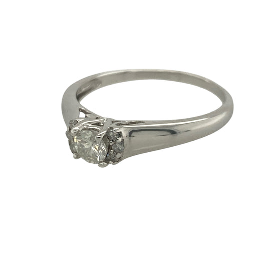 Add timeless elegance and exceptional sparkle to your jewellery collection with this pre-owned 9ct white gold diamond solitaire ring, featuring a classic design enhanced with sparkling shoulder stones—perfect for engagements, special occasions, or sophisticated everyday wear.
Design: The ring showcases a stunning brilliant cut centre diamond weighing approximately 0.28ct, creating a beautiful focal point with impressive brilliance and fire.