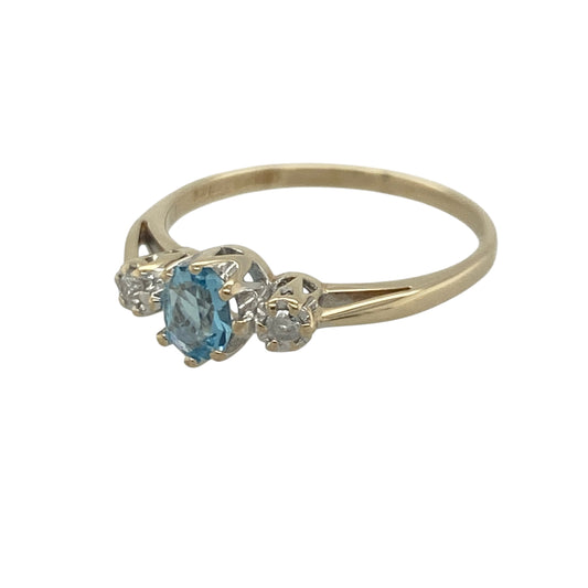 Add a touch of vibrant colour and timeless sparkle to your jewellery collection with this pre-owned 9ct yellow gold diamond and blue topaz trilogy ring, featuring a classic three-stone design with elegant everyday appeal—perfect for gifting, special occasions, or refined daily wear.
Design: The ring showcases a beautiful oval blue topaz centre stone measuring approximately 5mm by 4mm, creating a delicate focal point with its fresh sky-blue colour.