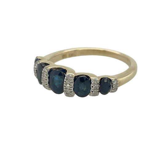 Add timeless elegance and rich colour to your jewellery collection with this pre-owned 9ct yellow gold diamond and sapphire band ring, featuring a classic gemstone design with refined everyday appeal—perfect for special occasions, gifting, or sophisticated daily wear.
Design: The ring showcases a beautiful sapphire centre stone measuring approximately 5mm by 3mm, creating an elegant focal point with its deep blue colour.