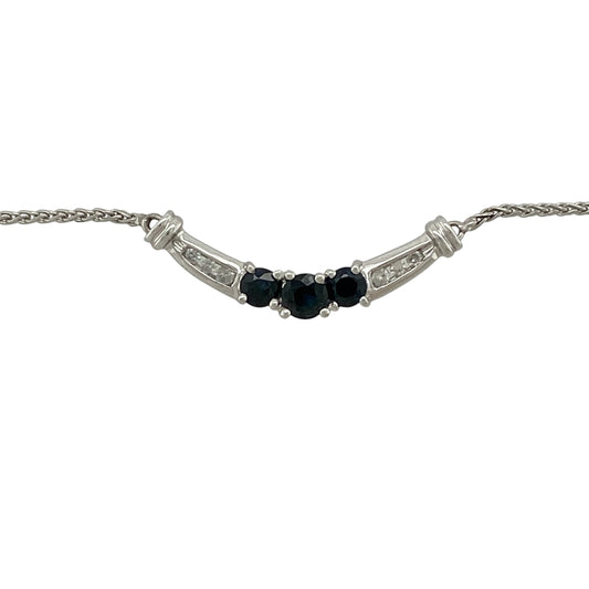 Add timeless elegance and vibrant colour to your jewellery collection with this pre-owned 10ct white gold diamond and sapphire curved bar necklace, featuring a graceful arrangement of sapphires and sparkling diamonds—perfect for everyday sophistication or special occasions.
Design: The necklace showcases an elegant curved bar design with a round sapphire measuring approximately 4mm in diameter at the centre, flanked by two round sapphires measuring approximately 3mm in diameter.