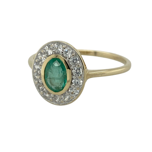 Add vibrant colour and timeless elegance to your jewellery collection with this pre-owned 9ct yellow gold emerald and cubic zirconia cluster ring, featuring a beautiful oval emerald surrounded by sparkling cubic zirconia stones.
Design: The ring showcases a striking oval emerald measuring approximately 7mm by 5mm, encircled by a halo of brilliant cubic zirconia stones that enhance the beauty and colour of the centre gemstone. The classic cluster design creates an elegant look with plenty of sparkle.