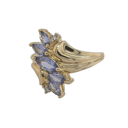 This pre-owned 9ct yellow gold diamond and tanzanite dress ring is a striking statement design, featuring five marquise cut tanzanite stones complemented by diamond detailing.
Design: Featuring a bold dress ring design, this ring has five marquise cut tanzanite stones arranged across the front with diamond detailing in warm 9ct yellow gold.
Material: Made from 9-carat yellow gold.
Gemstone Detail: Set with five marquise cut tanzanite stones, complemented by diamond detailing.