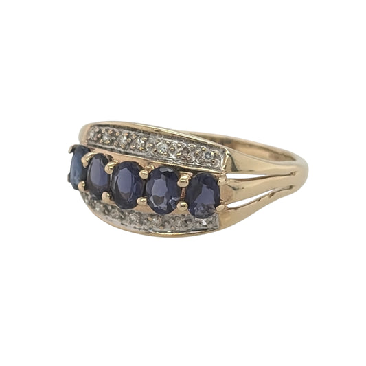 This pre-owned 9ct yellow gold diamond and iolite band ring is a distinctive gemstone design, featuring oval iolite stones complemented by diamond detailing.
Design: Featuring a wide gemstone band design, this ring has oval iolite stones arranged across the front with diamond detailing in warm 9ct yellow gold.
Material: Made from 9-carat yellow gold.
Gemstone Detail: Set with oval iolite stones measuring approximately 4mm by 3mm each, complemented by diamond detailing.