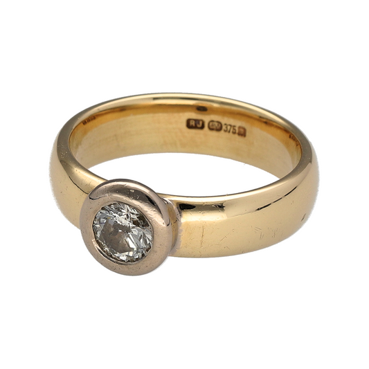 Make a confident and contemporary statement with this pre-owned 9ct yellow and white gold diamond rubover set solitaire wide band ring—an elegant design combining clean lines with impressive sparkle.
Design: The ring features a brilliant cut diamond weighing approximately 0.46ct, securely rubover set to create a smooth and modern finish. The 5mm wide band offers a bold, structured profile, giving the solitaire design a strong and distinctive presence on the hand.