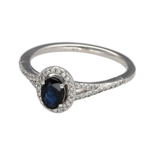 Load image into Gallery viewer, A beautiful halo of Diamonds surrounds a stunning Sapphire, suspended in the middle of the ring by the intricate mount. The Diamonds continue down the shoulders of the piece, elegantly matching the White Gold of the band creating more contrast between the Sapphire and the rest of the ring, while also adding to the design with their bewitching shimmer. A true masterpiece!
