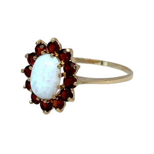 New 9ct Yellow Gold & Created Opal & Red Stone Flower Cluster Ring in size N to O with the weight 1.50 grams. The center stone is 8mm by 6mm