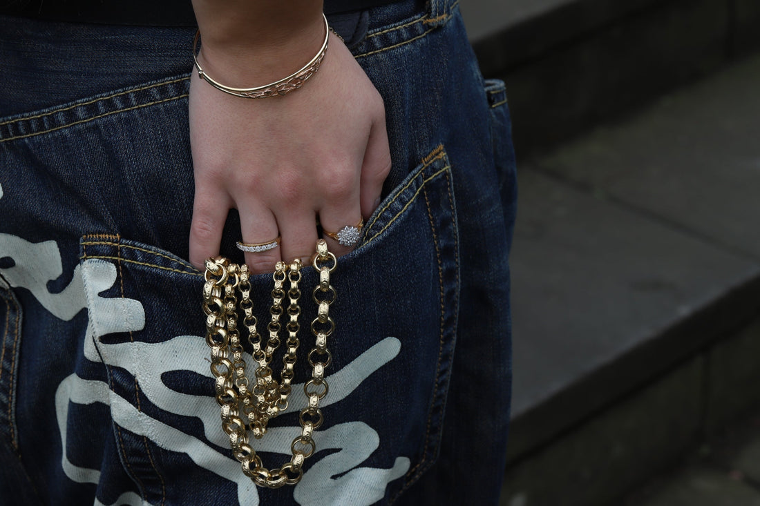 Hand in a pocket holding multiple gold chains