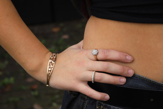 9ct Gold Clogau tree of life design Bangle with two Diamond set rings on a hand