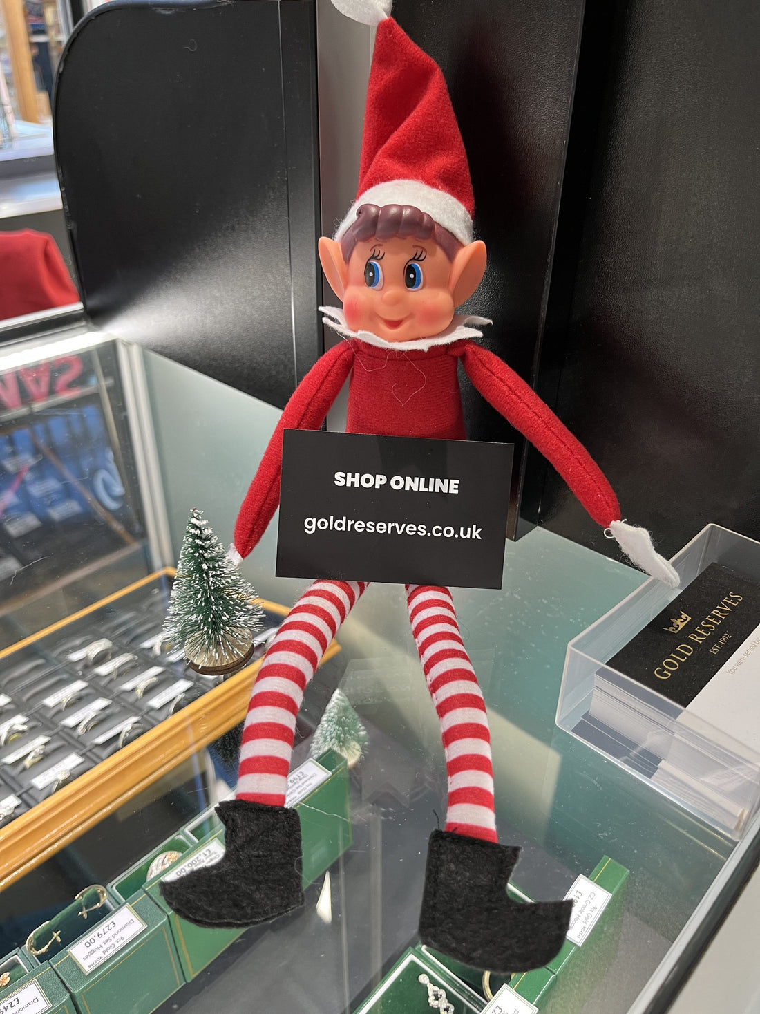 Christmas Elf holding jewellery business card in front of diamond gold rings