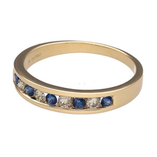 Load image into Gallery viewer, Bring classic elegance and rich contrast to your collection with this new 9ct yellow gold diamond and sapphire set band ring—perfect for everyday sophistication or a meaningful gift.

Design: The 4mm wide band features a row of channel-set sapphires and diamonds, offering a clean, structured look with timeless appeal.
Material: Made from 9-carat yellow gold, the polished finish enhances the depth of the sapphires and the sparkle of the diamonds.

