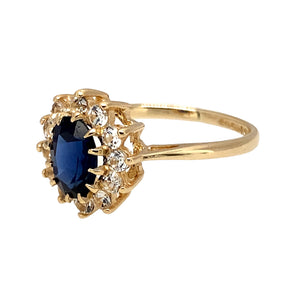 Preowned 9ct Yellow Gold Blue Stone & Cubic Zirconia Set Cluster Ring in size K with the weight 1.80 grams. The sapphire coloured blue stone is 7mm by 5mm