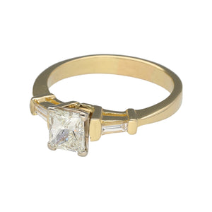 Preowned 14ct Yellow and White Gold & Diamond Set Emerald Cut Solitaire Ring in size V with the weight 6.10 grams. The center Diamond is approximately 1.10ct with a baguette cut Diamond on either side. The Diamonds are approximate clarity VS1 and colour N - R