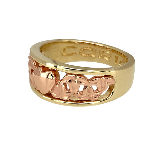 Celebrate love and heritage with this pre-owned 9ct yellow and rose gold Clogau Cariad heart band ring, a beautifully crafted piece rich in sentiment and Welsh tradition, featuring:

Design: An elegant wide band adorned with the word Cariad—Welsh for "beloved" or "darling"—and delicate heart motifs, symbolising love, connection, and cherished memories.
Material: Made from 9-carat yellow and rose gold, the two-tone design reflects