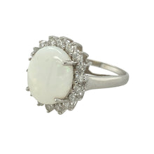 Load image into Gallery viewer, Add soft iridescence and vintage-inspired sparkle to your collection with this pre-owned 9ct white gold diamond and opalique cluster ring—a graceful design full of colour and charm.

Design: The ring features a 12mm by 10mm oval opalique stone at the centre, surrounded by a halo of brilliant-cut diamonds that enhance its luminous play of colour.
Material: Made from 9-carat white gold, the cool-toned setting perfectly complements the opalique&#39;s shifting hues and the bright sparkle of the diamonds.

